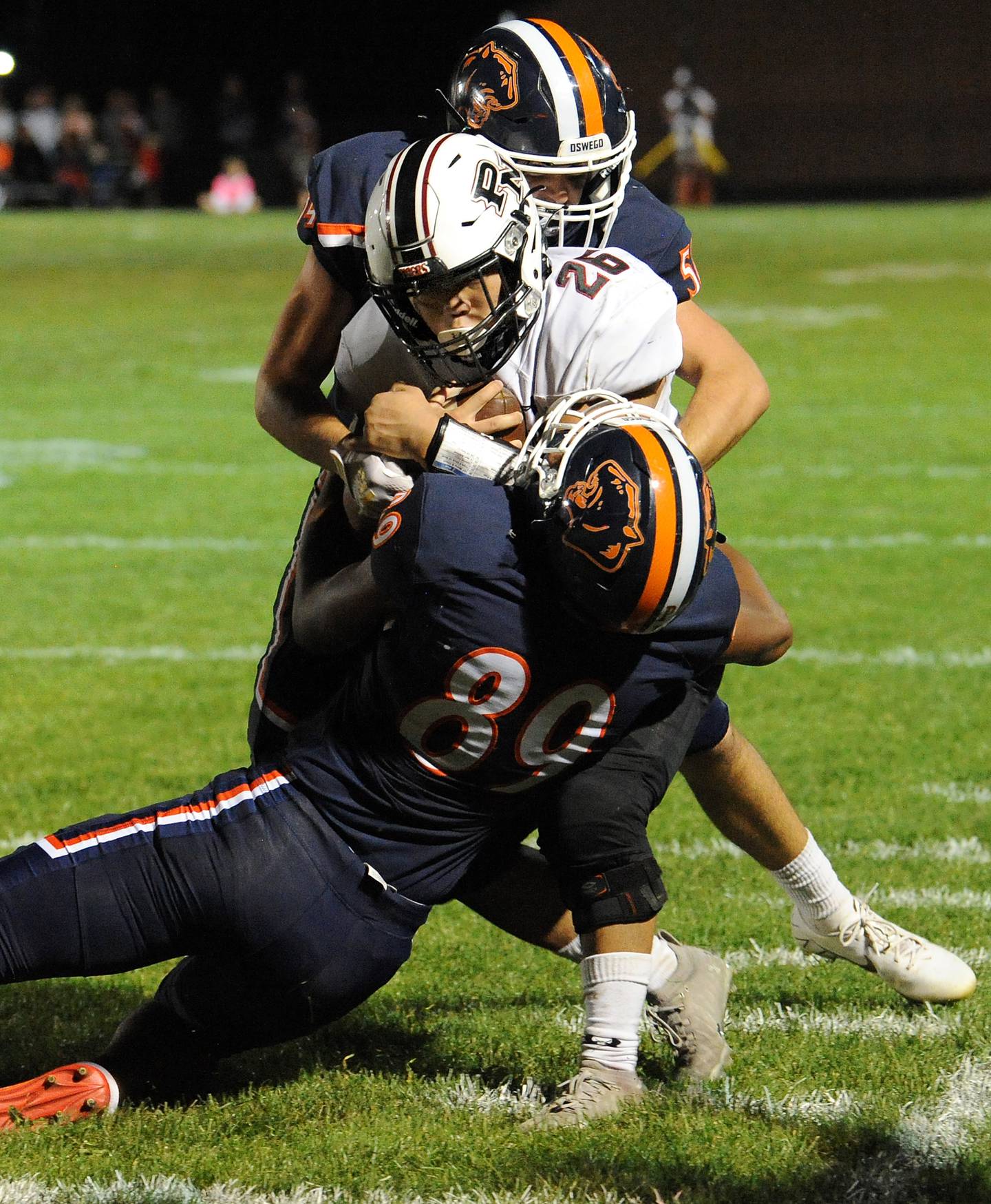 Plainfield North running back Jared Gumila (26) gets tackled out-of-bound by Oswego defensive end Taiden Thomas (89) and line backer Nate Perry (54) after gaining a first down during a varsity football game at Oswego High School on Friday.