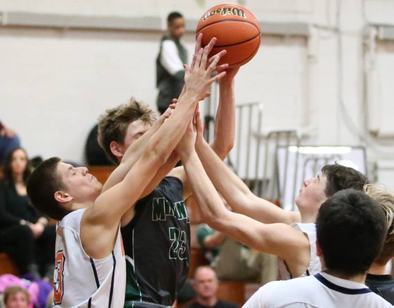 Midland's Ben Collins (center) grabs a rebound over Depue's Erick Perez (left) and Vance Hayes (right) on Monday, Dec. 19, 2022 at DePue High School.