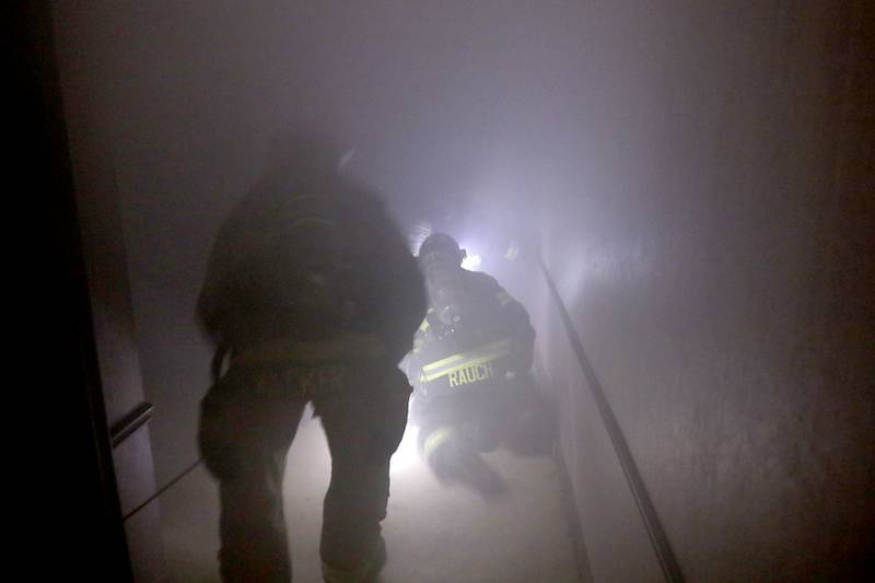 Algonquin firefighters from RIT team one  enter a smoke filled basement as they search for an injured firefighter on Tuesday April 15, 2025, during a RIT crew and chief divisional drill with other firefighters from area departments in a former bank building in Downtown McHenry.