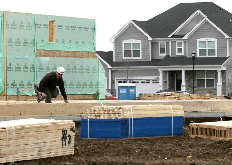 A construction worker builds a single family home Monday, April 4, 2022, in the Talamore of Huntley subdivision.