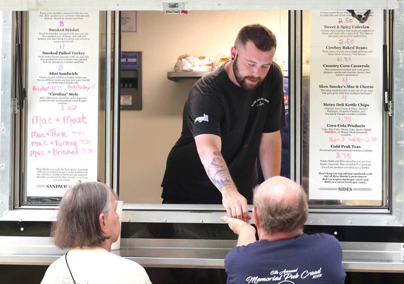Food truck operator Bob Dietz makes a sale at the Slow Smoke BBQ and Catering truck Tuesday, June 6, 2023, at the Sycamore Farmers’ Market, on the lawn of the DeKalb County Courthouse.
