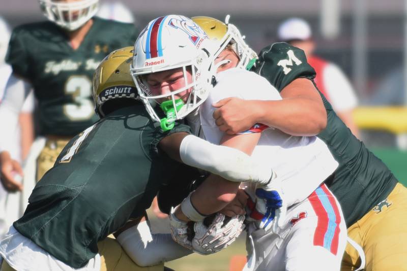 Marian Central's Max Kinney, center, is tackled by Bishop McNamara's Malachi Lee, left, and Ian Irps during a game at Bishop McNamara Saturday, Oct. 4, 2025.