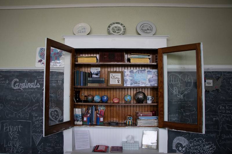 Open cabinet doors in a Davie School Inn guest room display globes and other teacher-themed decorations.