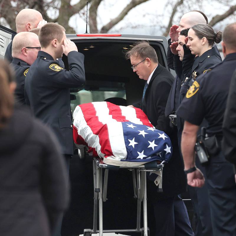 DeKalb County Sheriff’s Deputies salute as the flag-draped gurney carrying the body of DeKalb County Sheriff’s Deputy Christina Musil is removed from the Hearse Monday, April 1, 2024, at Butala Funeral Home following the processional honoring the fallen officer. Musil, 35, was killed Thursday while on duty after a truck rear-ended her police vehicle in Waterman.