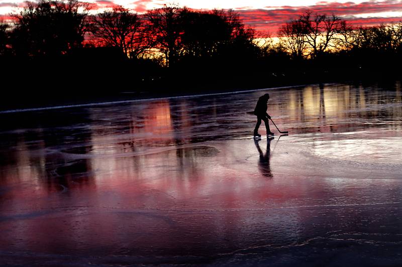 Rick Hudon controls the puck while skating and and pass a hockey puck with his son, River, on Wednesday, Jan. 8, 2025, on Crystal Lake near West Park.