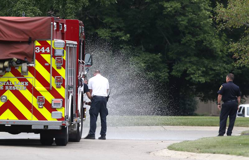 Firefighters spray water from a Crystal Lake Fire Department truck at the scene where four people were killed on Wednesday Aug. 9, 2023, in the 5800 block of Wild Plum Road in unincorporated Crystal Lake.