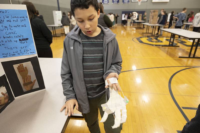 Sixth grader Danny Rodriguez show off his mechanical cardboard hand during a STEM exhibit at Challand Middle School in Sterling Thursday, March 9, 2023. The hand can pick up small and light objects. Students were allowed to freely choose they exhibits with sixth graders choosing a model base and eighth graders an experiment based display.