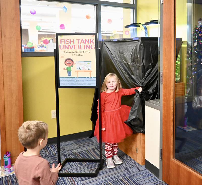 Lilith Mai, 4, of Ottawa, unveils the new aquarium at Reddick Library on Saturday Dec. 16.