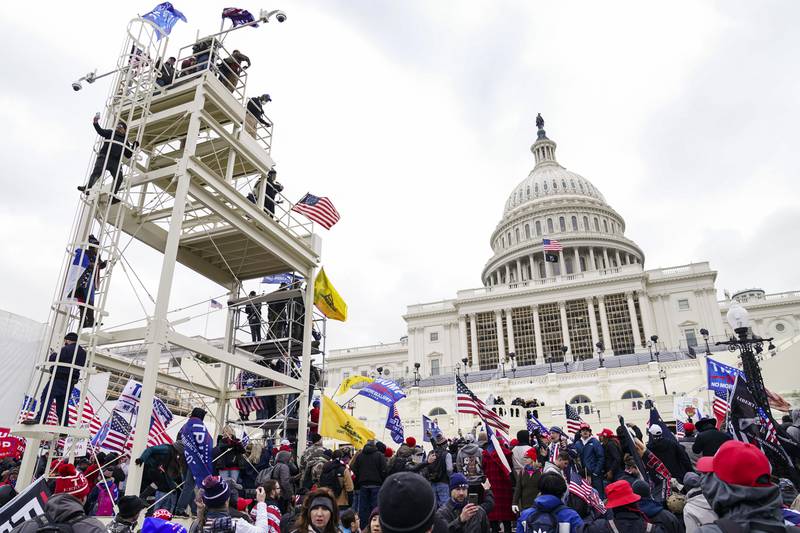 FILE - Violent insurrectionists loyal to President Donald Trump breach the U.S. Capitol in Washington, Jan. 6, 2021. John Banuelos, of Summit, Ill., who was accused of climbing scaffolding and firing a gun in the air during the riot was arrested Friday, March 8, 2024. Banuelos was charged with several felony and misdemeanor counts, including firearm charges. (AP Photo/John Minchillo, File)