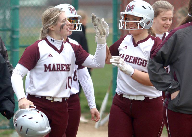 Marengo’s Lilly Kunzer, left, is greeted by Mia Feidt after Kunzer homered to clinch a win against Harvard in varsity softball at Marengo Thursday.