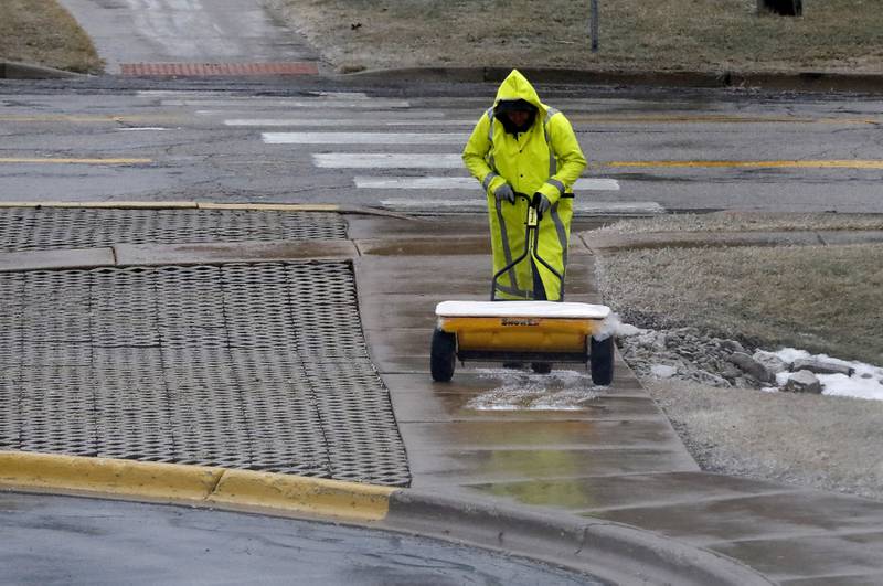 Salt is spread on an icy section of a sidewalk at the McHenry County Administration Building in Woodstock on Wednesday, Feb. 22, 2023, as a winter storm that produced rain, sleet, freezing rain, and ice moved through McHenry County.