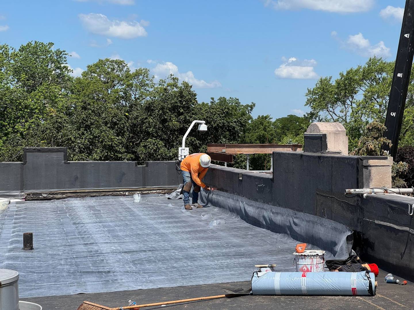 Workers repairing the roof on the west side of LTHS Central Campus in July 2025.