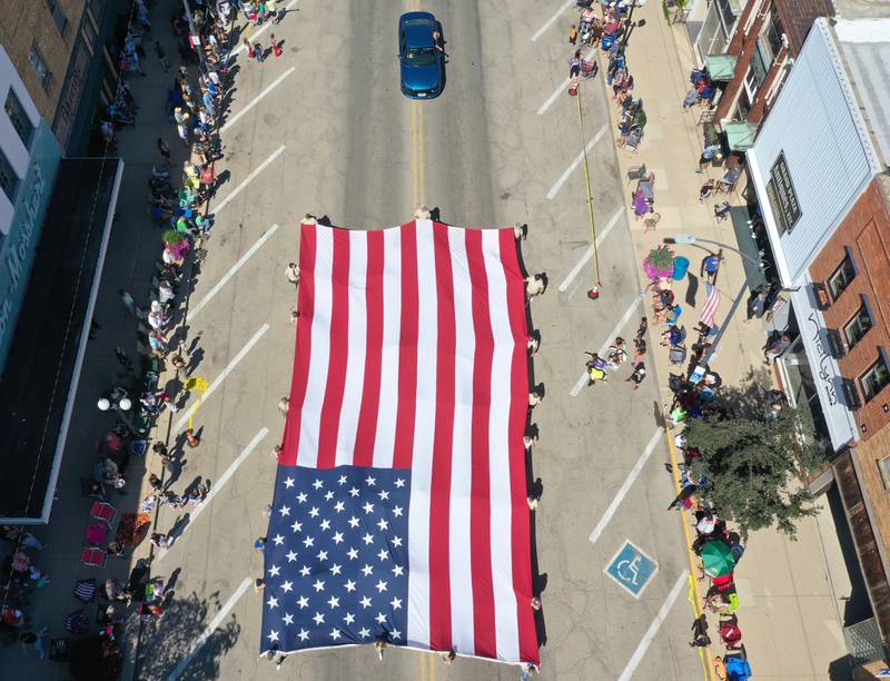 A large American Flag is carried by volunteers down Main Street during the 52nd annual Homestead Festival parade on Saturday, Sept. 9, 2023 in Princeton.