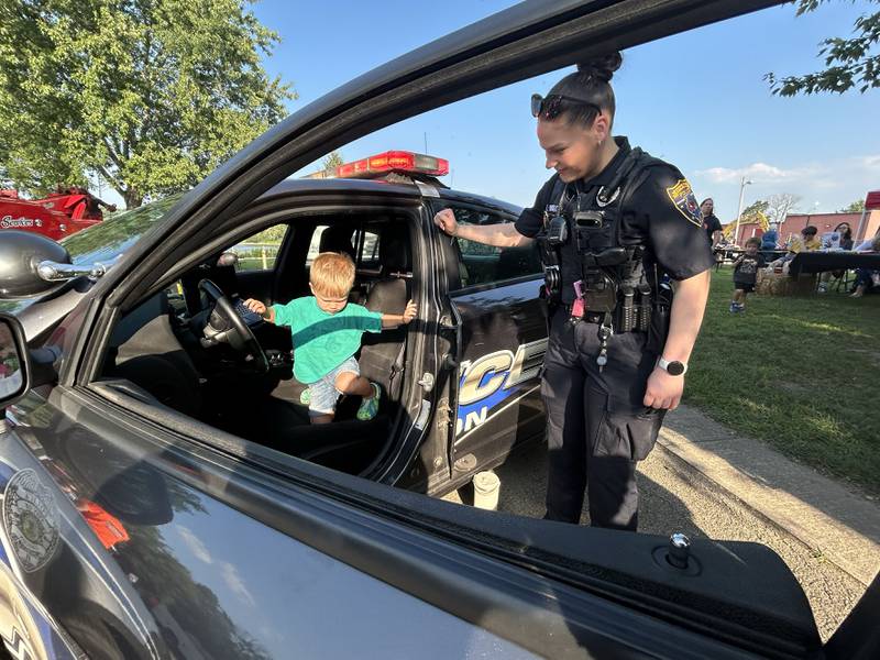Oregon Patrol Officer Taylor Buckwalter helps Reed Wehmhoefer, 2, of Oregon, out of her squad car at the National Night Out event in Oregon on Tuesday, Aug. 5, 2025. The event was organized by the Oregon Police Department and included displays and trucks provided by the fire department and public works departments.