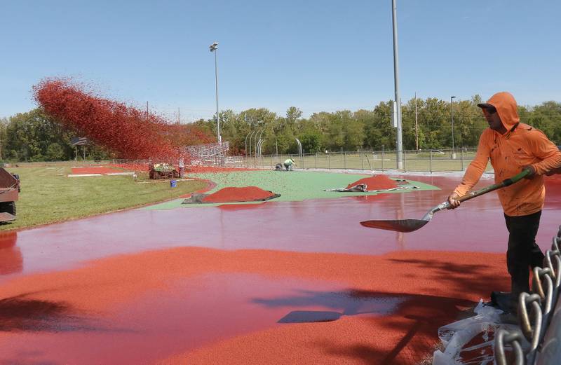A worker with Track Surfaces Company in Elburn, shovels red dyed cinder onto the La Salle-Peru Township High School Track on Tuesday, Sept. 23, 2025 at the La Salle-Peru Township High School Athletic Complex in La Salle. Crews have been resurfacing the track for the past week. LaSalle-Peru Township High School Sports Complex will be closed to the public for approximately four weeks while the track undergoes resurfacing work. The track was first installed in 2014.