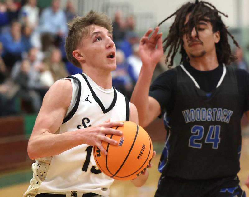 Sycamore's Xander Lewis goes to the basket in Woodstock's Jeremy Stokes Woodstock's Jeremy Stokes Friday, Feb. 27, 2026, during their IHSA Class 3A boys basketball regional championship game at Boylan Catholic High School in Rockford.