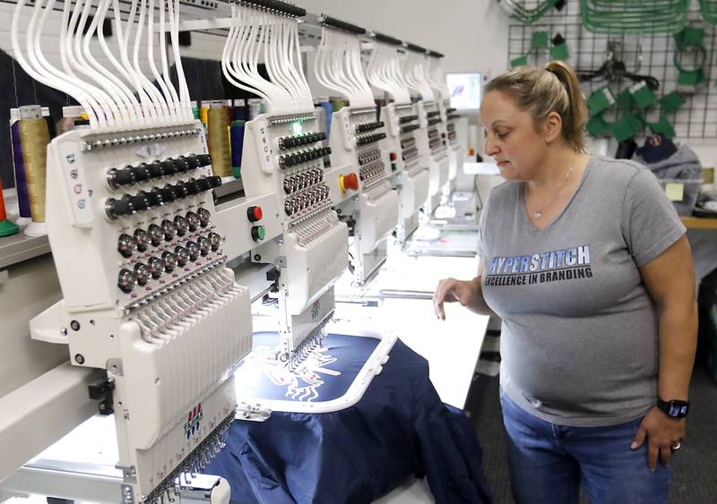 Sara White, the owner of Hyperstitch, checks the operation of an embroidery machine on Monday, Oct. 23, 2023, at the business in Marengo.