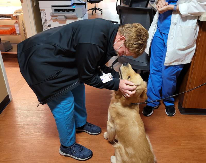 Dolores Abreu, a patient care technician, enjoys a visit from therapy dog Holly on National Rural Health Day at Northwestern Medicine Valley West Hospital.