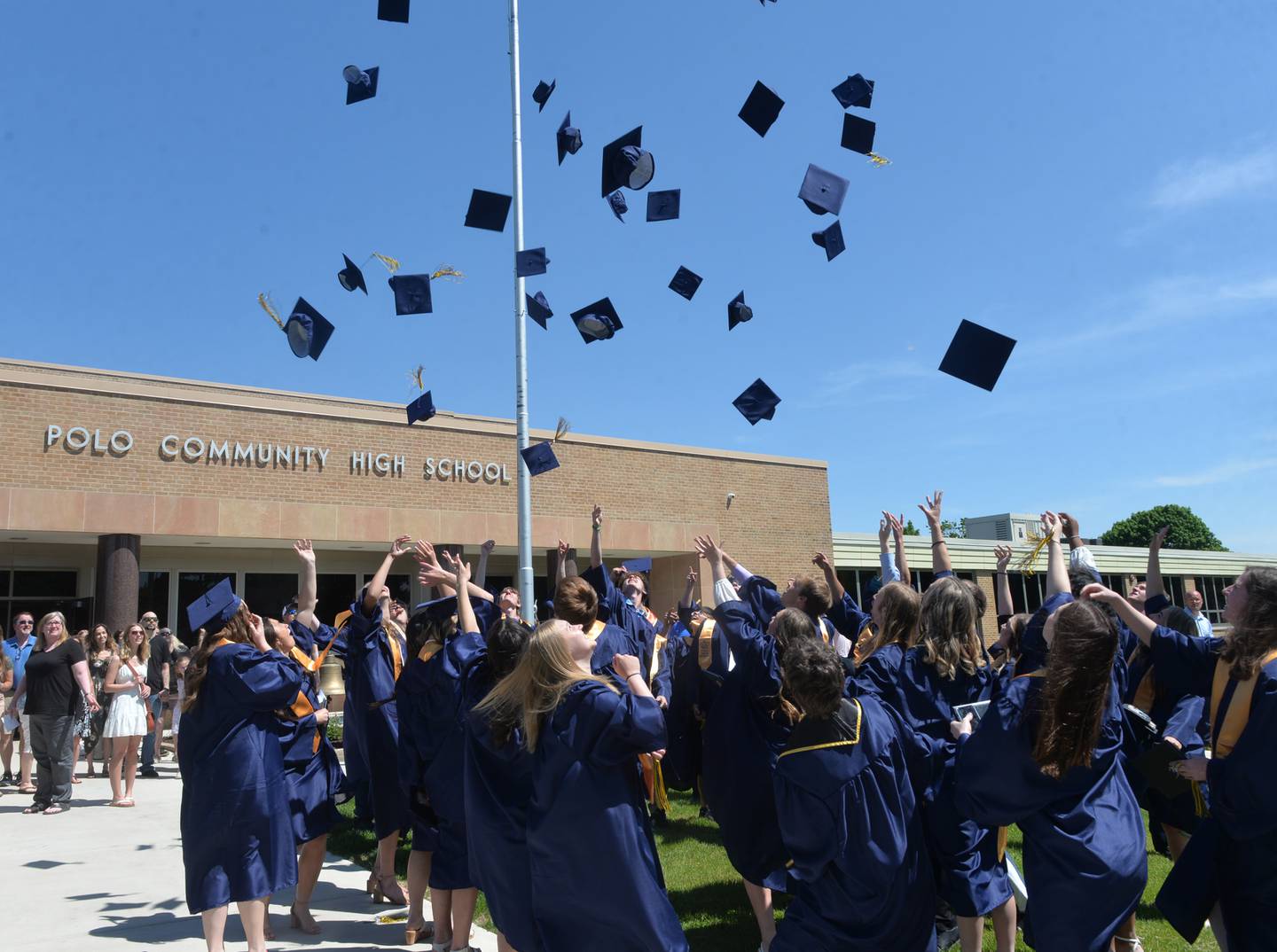 Polo High School graduates toss their caps into the air after exiting the high school following their commencement on Sunday, May 21.