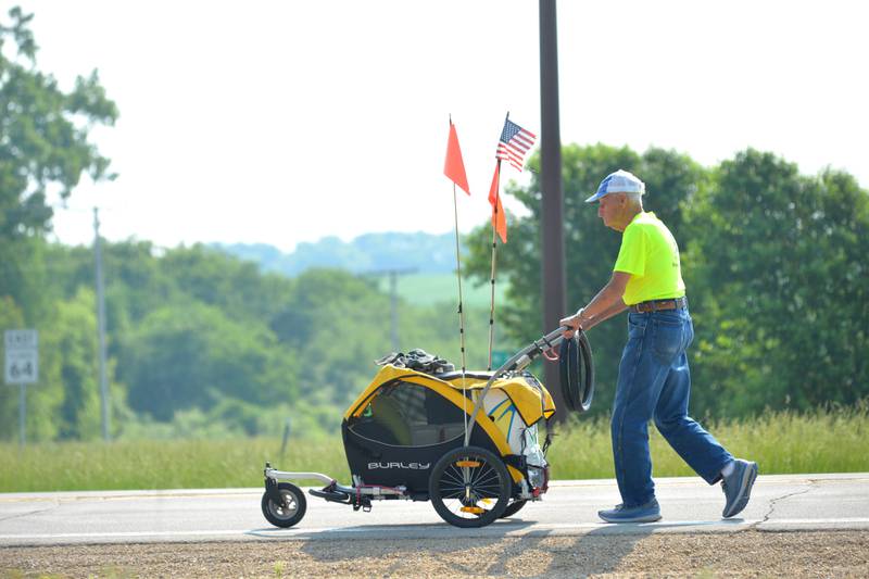 Dean Troutman pushes his cart north on Illinois 26 as he heads to Forreston after enjoying breakfast at the Dogwood Inn. Troutman, 92, of Princeville, Illinois, is walking to raise money for St. Jude's. He spent Saturday night at the Polo Ambulance Office and will spend Sunday night at the Forreston Fire Station before heading north to Freeport.
