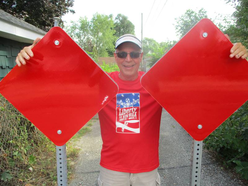 Cunningham Neighborhood Council President John Sheridan stands with the posts and signs that block access again to the Joliet alley behind his house. Aug. 23, 2023.