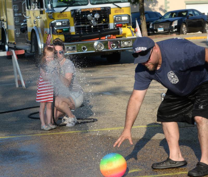 Maeve Hassett, 4, of Centennial, Colorado, gets some help from her mom, Katie, a Mt. Morris native, during the kids' water fight at Let Freedom Ring on Monday. The event was organized by the Mt. Morris Fire Department.