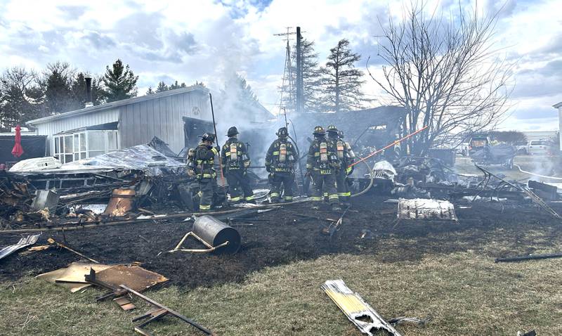 Firefighters look for hot spots in a charred and collapsed recreational vehicle following a garage fire at 6727 W. Henry Road, southeast of Polo, on Wednesday, March 26, 2025. Several departments responded to the fire at the rural residence.