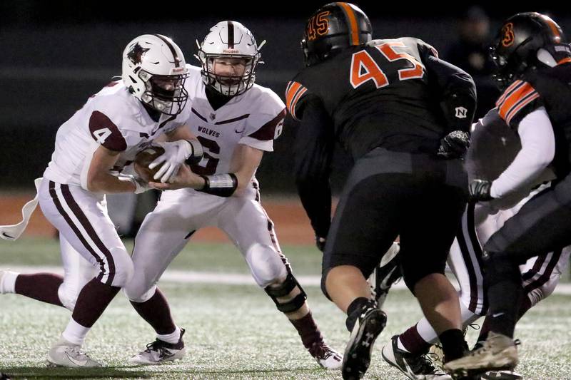 Prairie Ridge quarterback Taidhgin Trost, center, fakes a handoff to teammate Ty Baker, left, against McHenry during their season opening football game at Huntley High School on Friday, March 19, 2021 in Huntley.