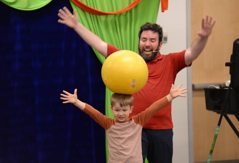 Teddy Van Stevenson assists Jason Kollum with one of his juggling acts during the See a Juggler, Be a Juggler held at the Glen Ellyn Library Saturday April 5, 2025.