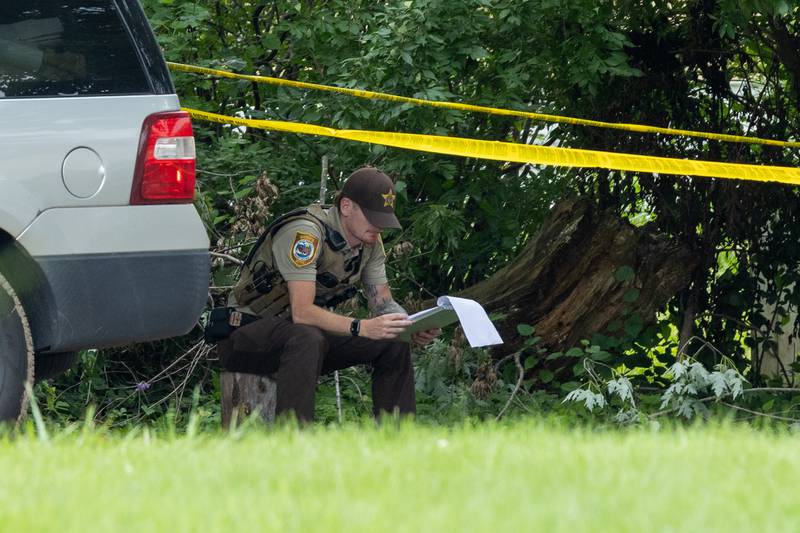 La Salle County Sheriff's Deputy sits behind caution tape at the crime scene of a double homicide on Thursday, July 17, 2025, on 42nd Road in Sheridan.
