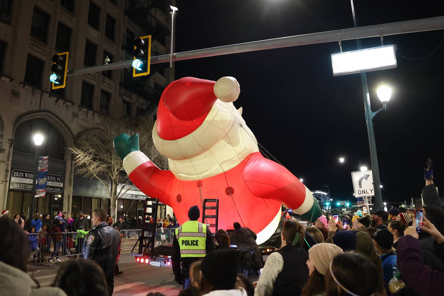 The crowd videos and cheers as the Santa does the limbo under the Chicago Street sign at the end of the parade at the Light Up the Holidays Festival and Parade in downtown Joliet.