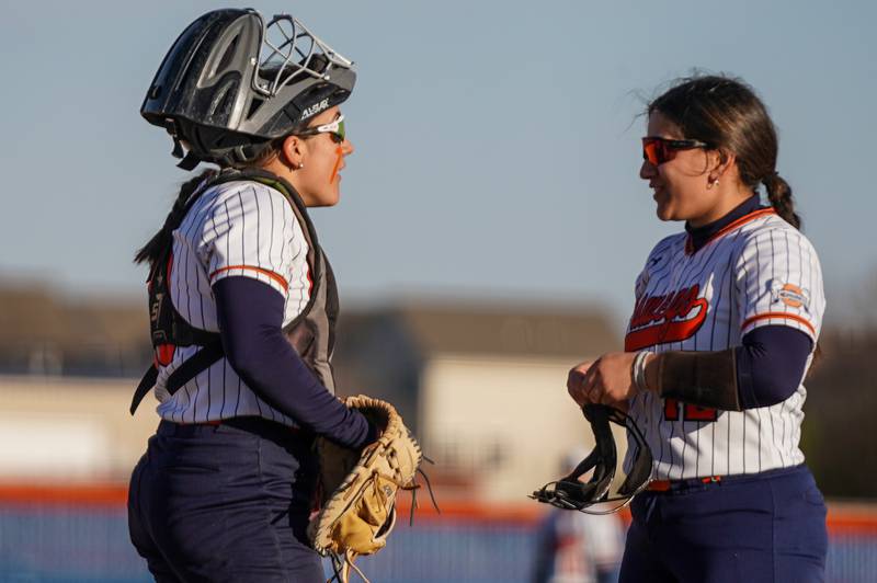 Oswego’s Kiyah Chavez (left) talks to Aubriella Garza (right) during a softball game against Downers Grove South  at Oswego High School on Tuesday, March 19, 2024.
