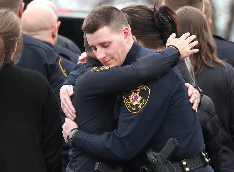 DeKalb County Sheriff’s Deputies hug following the processional honoring DeKalb County Sheriff’s Deputy Christina Musil Monday, April 1, 2024, at Butala Funeral Home in Sycamore. Musil, 35, was killed Thursday while on duty after a truck rear-ended her police vehicle in Waterman.