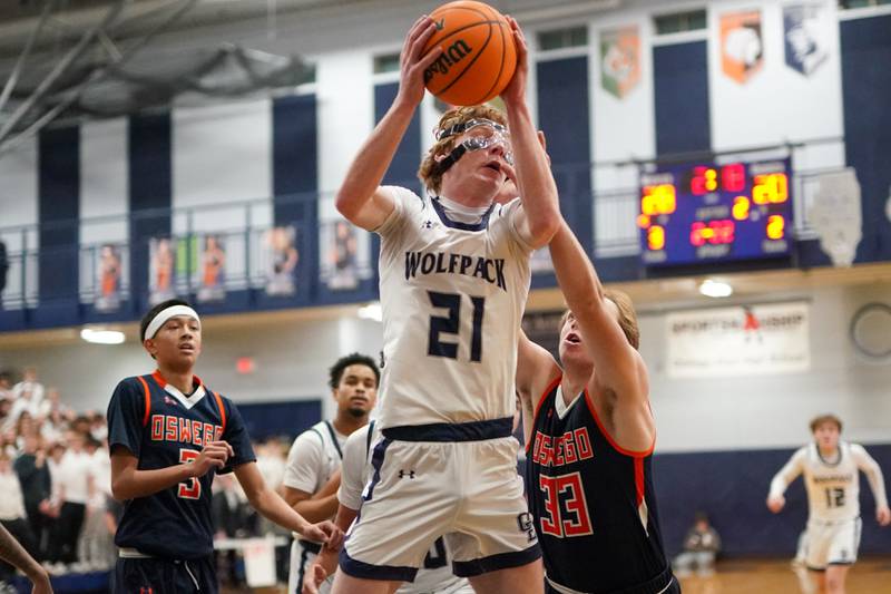 Oswego East's Andrew Pohlman (21) rebounds the ball against Oswego during a basketball game at Oswego East High School on Saturday, January 14, 2017.
