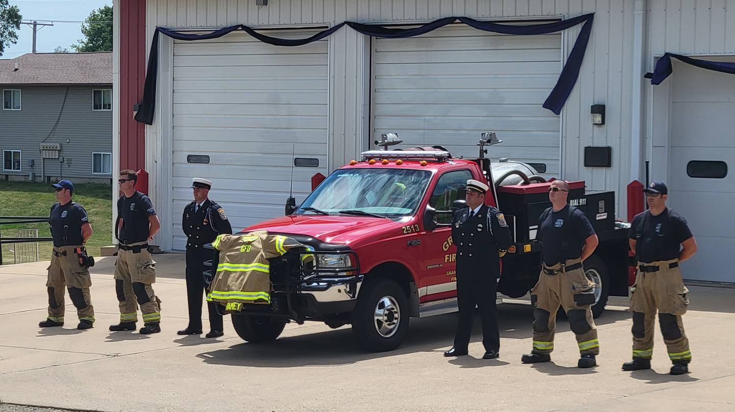 Firefighters from the Granville Fire Department stand at attention as the funeral procession for one of its own, the late Arthur Ramey, passes by on Saturday afternoon. Displayed on the front of the truck is Ramey's coat.