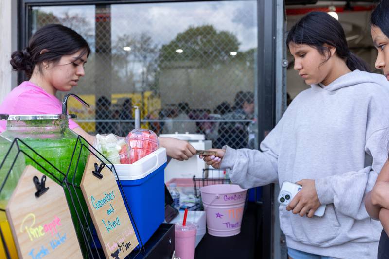 (Left) Karina Coronel of “La Esquinita de Oro Ice Cream Shop” gets handed money by (Right) Hannah Lopez on Friday, May 2, 2025 at Northbrook School in Mendota.