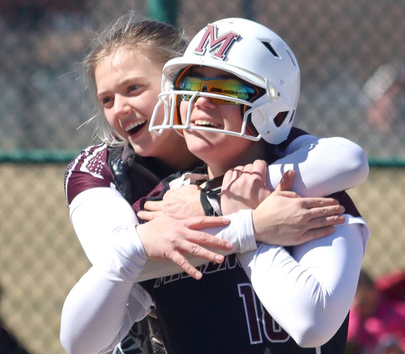 Marengo’s  AJ Pollnow, front, is embraced by teammate Kylee Jensen, left, after Pollnow belted a grand slam against North Boone in varsity softball at Marengo High School in Marengo on Saturday, March 22, 2025.