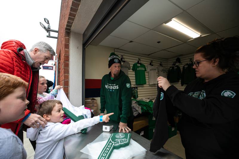 John Newell, left, helps his son Janes, pointing, pick out a   Chicago Hounds t-shirt before the start of the match at Seat Geek Stadium in Bridgeview, on Sunday April 23, 2023. Newell and his other two children Thomas, left, and Sawyer, rear, came from Winnetka for the game.