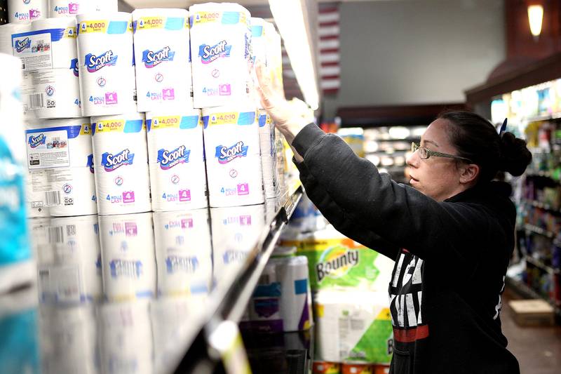 Ali Clyne stocks the shelves with toilet paper at the Blue Goose Market in St. Charles on March 13.