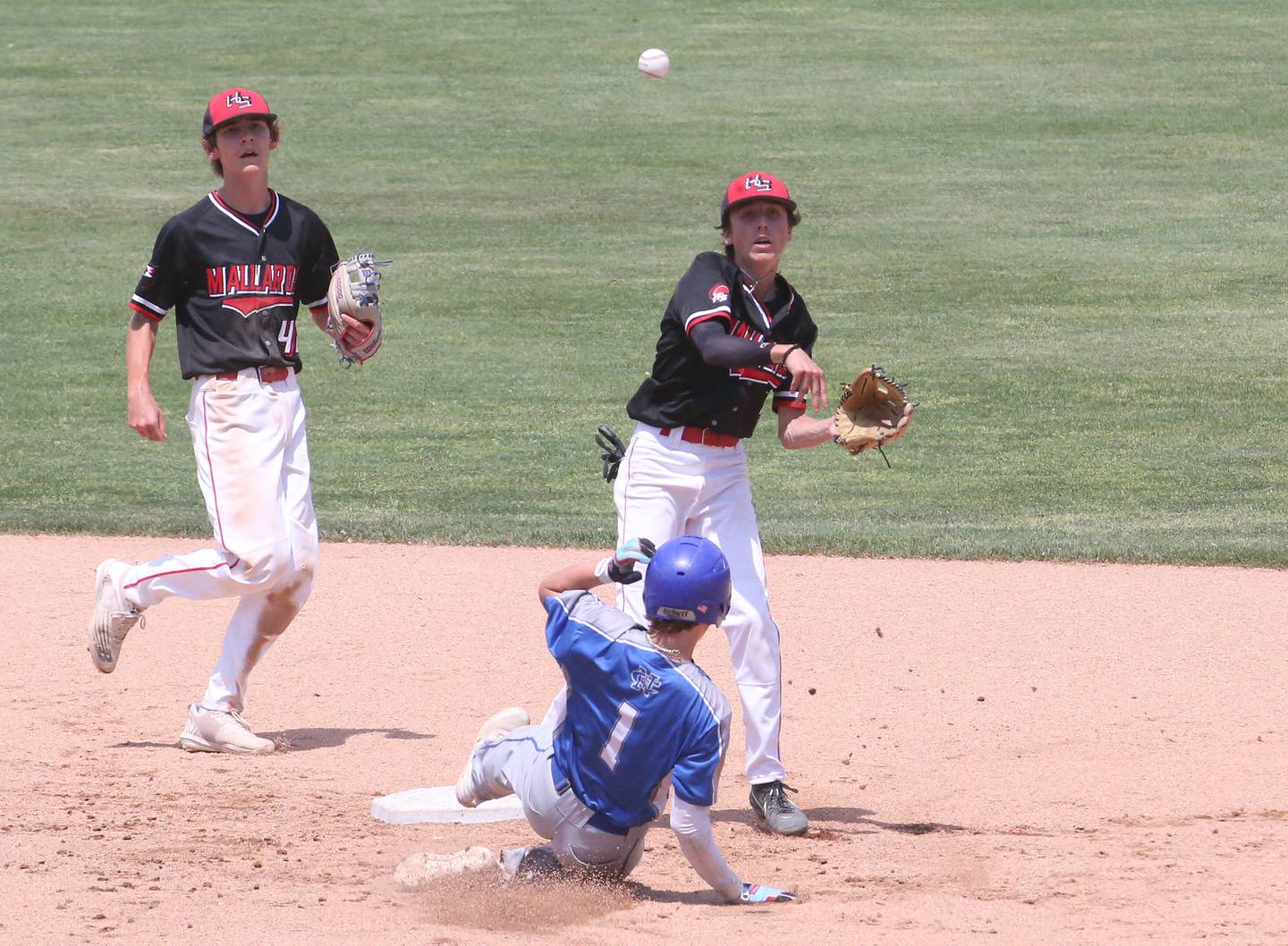 Henry-Senachwine's Teagan Williams throws to first base as teammate Carson Rowe backs him up while turning a double play on Newman's Garrett Matznick during the Class 1A State semifinal game on Friday, June 2, 2023 at Dozer Park in Peoria.