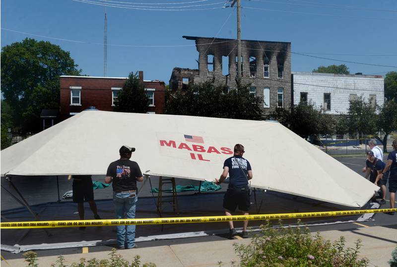 Sterling fire department officials installed a large Mutual Aid Box Alarm System (MABAS) tent on Monday July 10, 2023, in the Wipfli parking lot across from the charred apartment building at 406 E. Third St. in Sterling that was destroyed by an early morning fire on Friday.
