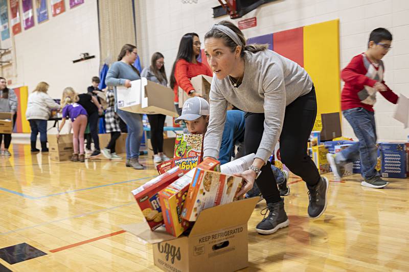 Volunteering for the Palmyra Hillbillies 4H club, Lindsay Melendrez and son Drew, 9, push full boxes of food across the gymnasium floor at the Dixon YMCA.