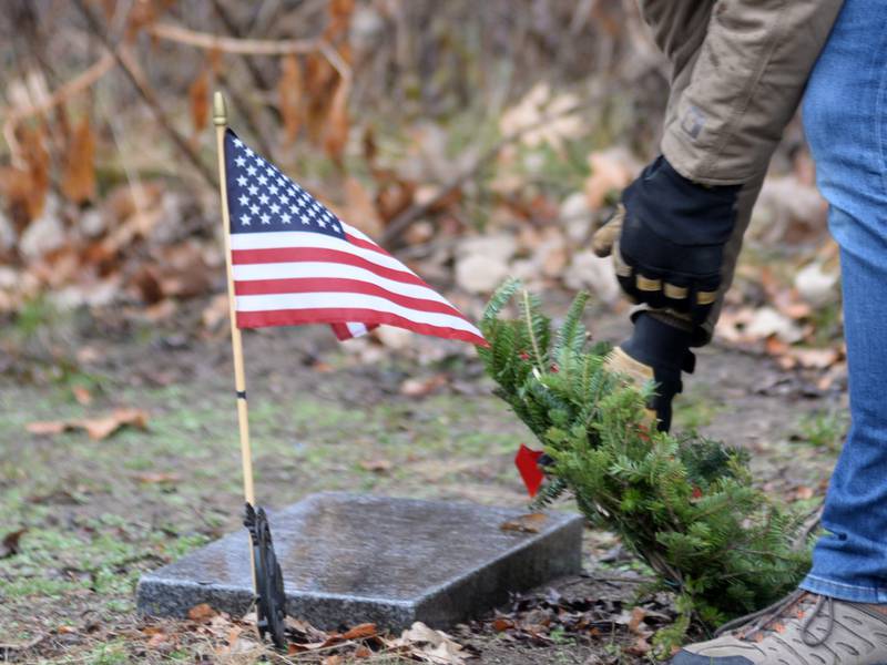 Luke Becker of Oregon, places a wreath at a veteran's grave during the Wreaths Across America event at Daysville Cemetery. east of Oregon, on Saturday, Dec. 16, 2023. Luke and his daughters, Lana,   Aven and Remy helped at the event.