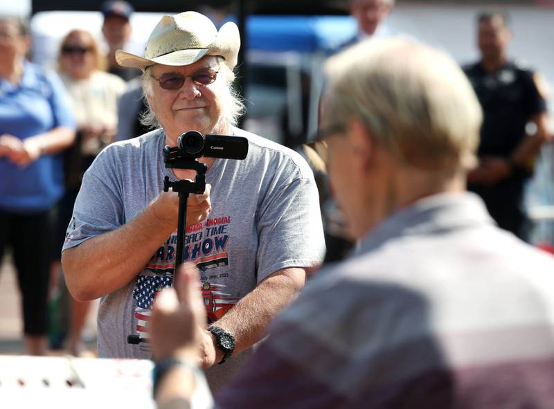 Mike Tritle, from DeKalb, shoots video Thursday, Aug. 22, 2024, as U.S. Air Force veteran Michael Embrey speaks during the DeKalb Veterans Memorial Mural dedication in Van Buer Plaza in DeKalb. Tritle captures the stories of veterans on video during at community events in the area.