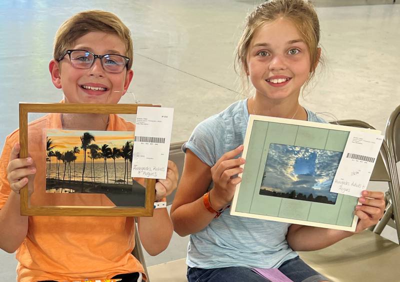 4-H members Ryan and Ava Perreault of Oswego hold up their photography projects as they wait to be judged at the Kendall County 4-H Shows earlier this month.