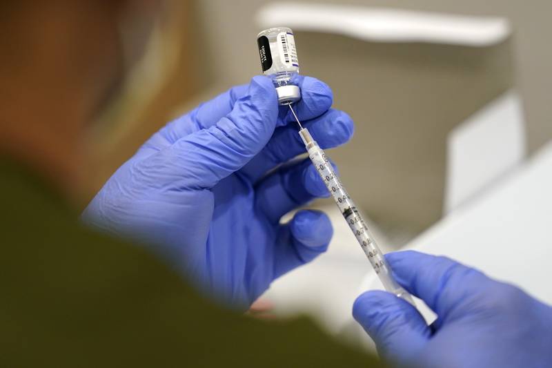 FILE - A healthcare worker fills a syringe with the Pfizer COVID-19 vaccine at Jackson Memorial Hospital on Oct. 5, 2021, in Miami.   U.S. regulators have opened up COVID-19 booster shots to all and more adults, Friday, Nov. 19, letting them choose another dose of either the Pfizer or Moderna vaccine.