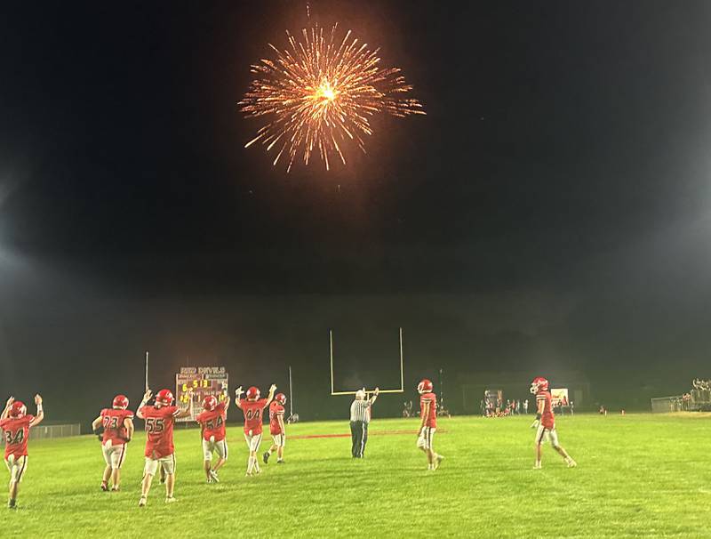 Members of the Hall football team celebrate after scoring a touchdown against Sherrard as firewoks glow in the background on Friday, Sept. 19, 2025 at Richard Nesti Stadium.