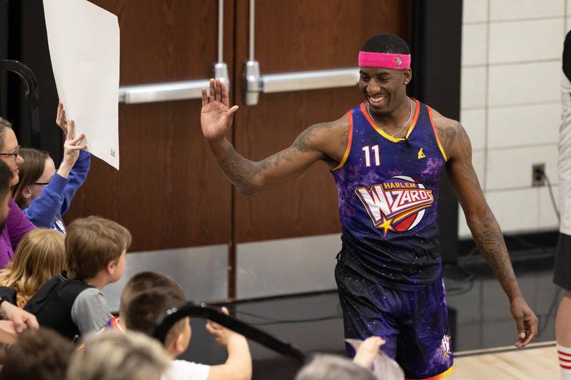 Kamil “Dragon” Brown (77) of the Harlem Wizards high-fives audience members on Wednesday, April 16, 2025 at Woodland High School in Streator.