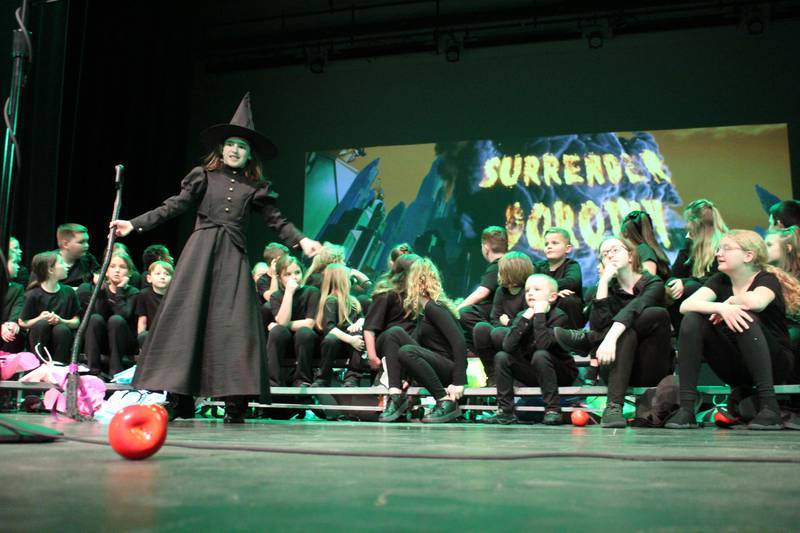 The Wicked Witch of the West (Alexandria Pedelty) demands the Emerald City "SURRENDER DOROTHY" as the ensemble looks on Friday, March 22, 2024, during the Streator Elementary Schools production of "The Wizard of Oz – Youth Edition" at Streator High School.