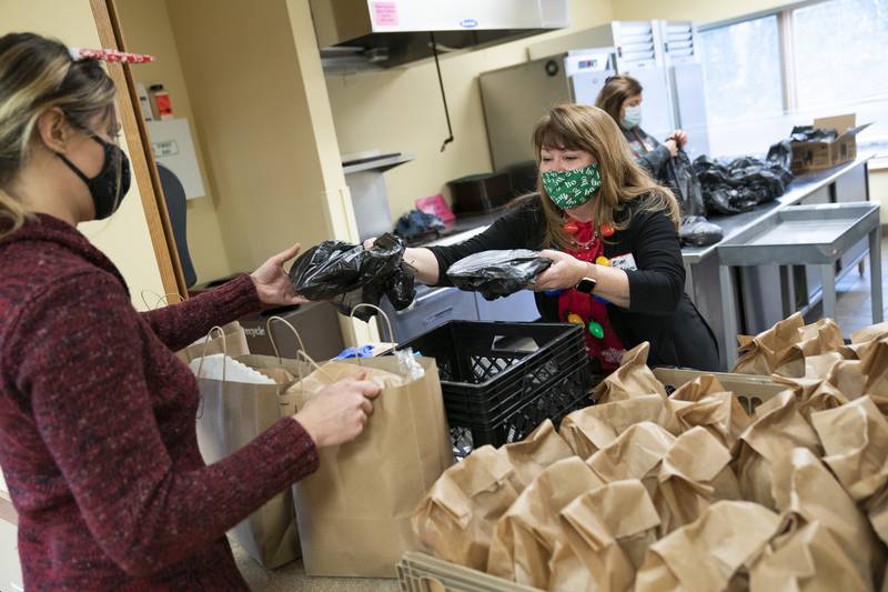 Volunteers Melissa Victor, left, and Ellen McAlpine package up meals for seniors during the second annual drive through Holiday Party in a Bag for local senior adults hosted by the Cary Park District on Thursday, December 23, 2021 at the Cary Community Center. The Holiday Party in a Bag included a holiday meal, small games and treats. Ryan Rayburn for Shaw Local
